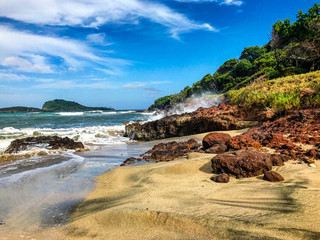 Waves crashing on red red rocks at beach