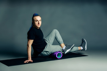 Portrait of a young man with an unusual hairstyle of mohawk from blue braids in sportswear doing...