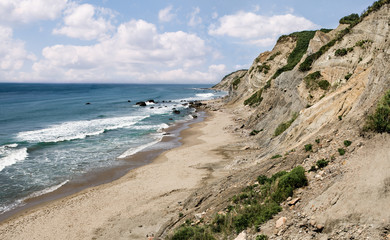 Cliffside Beach in Rhode Island:  Ocean waves break on a sandy beach beneath the tall cliffs of...