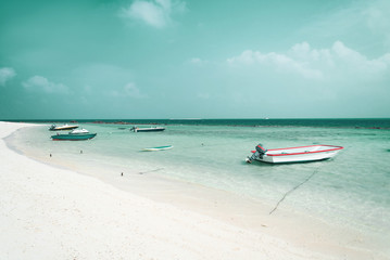Rajska tropikalna plaża, zakotwiczone małe łódki oraz motorówki. - obrazy, fototapety, plakaty