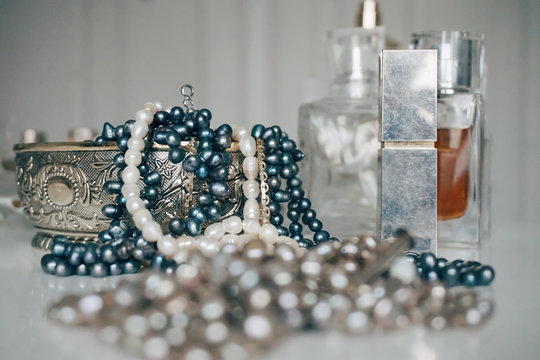 Close-up Of Pearl Necklaces And Perfumes On Table