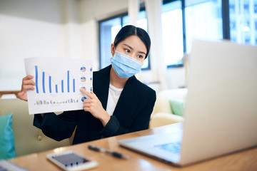 Young Asian woman wearing a face mask is having video conference at home office.
