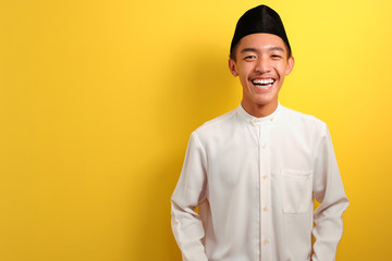 Smiling Young Asian Muslim man standing over yellow - obrazy, fototapety, plakaty