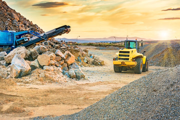 Excavator and stone crusher in a quarry - obrazy, fototapety, plakaty