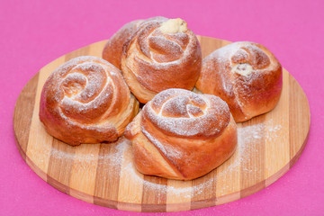 Pile of cheesecakes with caster sugar on a wooden round plate.