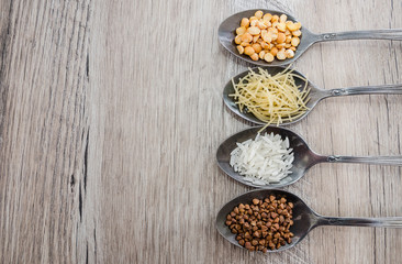 composition with various types of legumes and cereals in spoons on a wooden table, place for text. Organic grains.