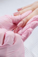 Woman in nail salon receiving manicure by beautician. Manicure process in beauty salon, close up. Close up of a woman hand with pink nail polish after the manicure.