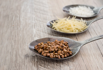 composition with various types of legumes and cereals in spoons on a wooden table. Organic grains. Macrons, rice and buckwheat. Close-up.