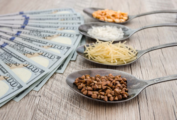 composition with various types of legumes and cereals in spoons on a wooden table. Organic grains and dollars. The concept of the economic crisis and rising food prices.