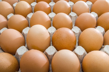 Chicken eggs in a cardboard box on a wooden table.