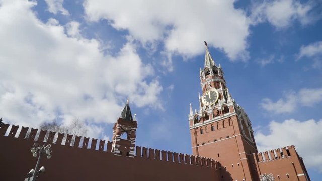 Red Kremlin fortress and Spasskaya tower on background of blue sky. Action. Top of red fortress wall and Kremlin clock tower