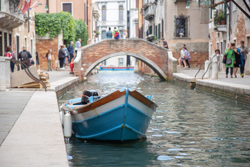 Fototapeta na wymiar Moored boat in one of the water canals of Venice but in the midst of a bustling city
