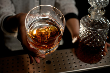 close-up of glass with alcoholic drink in bartender's hand
