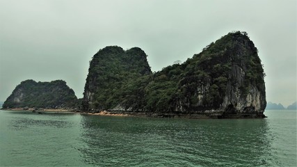Fototapeta premium Rainy and foggy day in Halong Bay. Forest covered islands rise straight from the water.