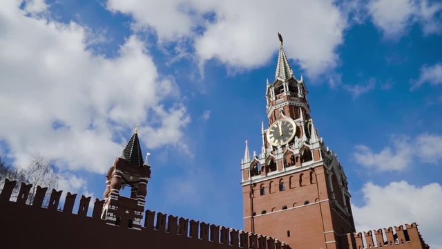 Red Kremlin fortress and Spasskaya tower on background of blue sky. Action. Top of red fortress wall and Kremlin clock tower