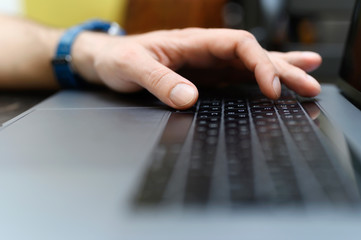 male hand typing on the keyboard a laptop. working man programmer. work from home. workplace with a laptop. selective focus