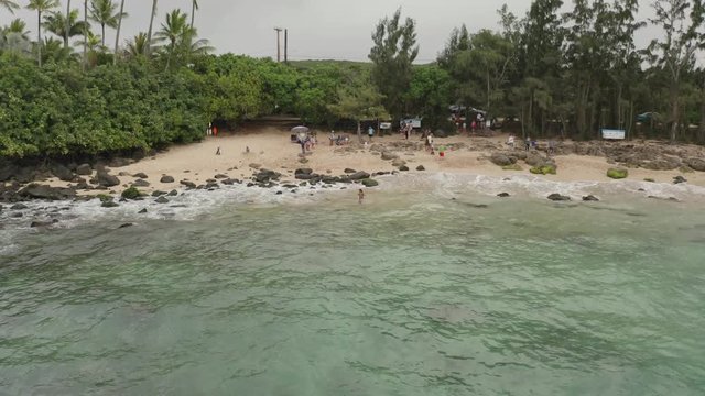 Flying along the shoreline of Laniakea Beach on the island of Oahu, Hawaii with overcast skies.