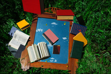 Colorful books falling from sky into a vintage mirror,no person,outdoors,playful scenery