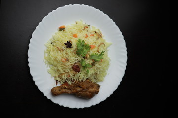 Chicken Biryani showing leg piece - It's a delicious recipe of Basmati rice mixed with with spicy marinated chicken in a bowl.  Served in a bowl or plate. Selective focus