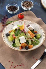 Fresh Greek salad in bowl with olives tomato feta cheese cucumber and onion on textile napkin