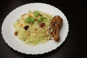 Chicken Biryani showing leg piece - It's a delicious recipe of Basmati rice mixed with with spicy marinated chicken in a bowl.  Served in a bowl or plate. Selective focus