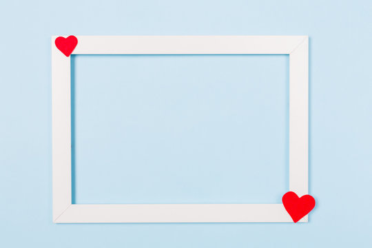 White frame empty blank picture with red heart on light blue background . Copy space free text. Holiday card concept. Mock up. Greeting. Mother's Day. St Valentine's Day. Love . Wedding invitation. 