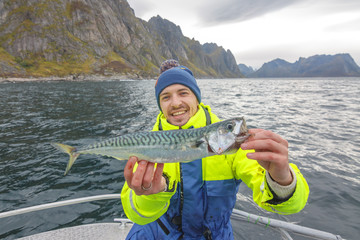 Happy fisherman with mackerel fish in hands