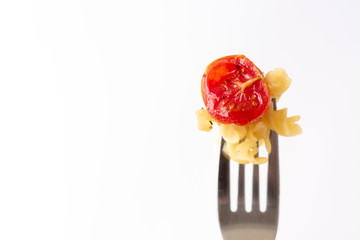 A fork holding Italian pasta fusilli with backed tomato on a white background with copy on the left