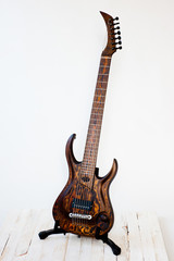 Seven-string electric guitar made of dark wood. Shot on a white background. Background for music and creativity.
