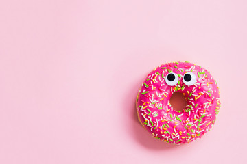 Pink donut with eyes on a pink background