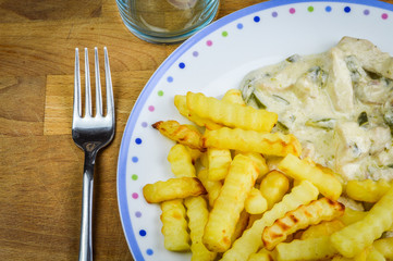 Chopped raw chicken breasts and knife on a wooden chopping board