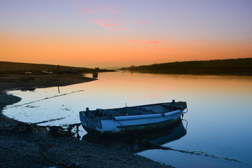 Moored boat on Chesil Beach at sunset