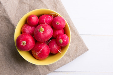 Yellow plate with radish on a white table
