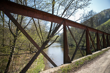 Iron cross  element of a bridge with river view in a forest early in the spring