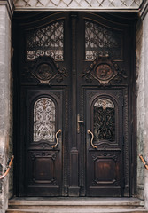 An old dark brown wooden door of the Jesuit Church in Lviv. Beautiful carvings in mahogany. Entrance to the temple. Apostle Paul and Apostle Peter.