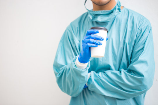 Midsection Of Doctor Holding Disposable Cup Against White Background