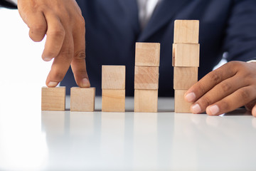 Businessman Wooden cubes on a desk in the office, Concept: Business to succeed that challenges teamwork, design development strategy investment, symbol Financial advisor shows  to asset growth