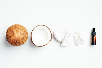 Coconut with essential oil on white background. Flat lay composition, top view. Body care, SPA treatment concept