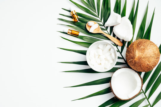 Natural organic cosmetic and coconut with tropical palm leaf on white background. Flat lay, top view, copy space. Body care and skin treatment concept
