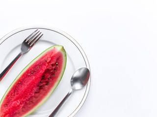 Sliced Watermelon on white plate with spoon and fork stock photo with bright background.
