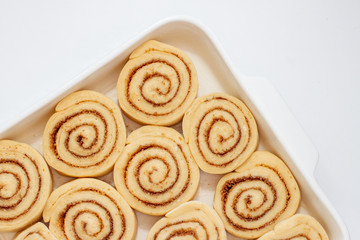 Cinnamon rolls dough preparation in a baking dish. Raw buns on Ceramic baking dish