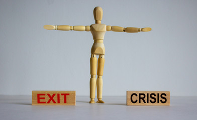 COVID-19 Pandemic Coronavirus concept. Wooden blocks with words 'exit crisis'. Wooden model of human.