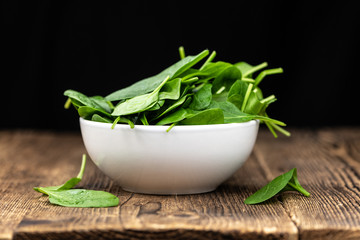 Old wooden table with fresh Spinach (selective focus; close-up shot)