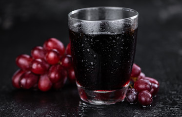 Fresh made Red Grape Juice on a slate slab (close-up shot; selective focus)