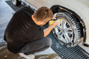 man cleaning car with yellow sponge. carwash concept