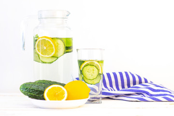 Health care, fitness, healthy eating concept. Fresh cool lemon cucumber drink with water, cocktail, detox drink, lemonade in a glass jug and a glass. cucumbers and lemon on a plate