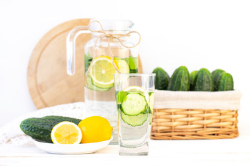 Health care, fitness, healthy eating concept. Fresh cool lemon cucumber drink with water, cocktail, detox drink, lemonade in a glass jug and a glass. cucumbers and lemon on a plate