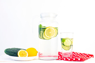 Health care, fitness, healthy eating concept. Fresh cool lemon cucumber drink with water, cocktail, detox drink, lemonade in a glass jug and a glass. cucumbers and lemon on a plate