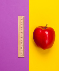 Apple, wooden ruler on purple yellow background. Back to school. Education concept. Top view