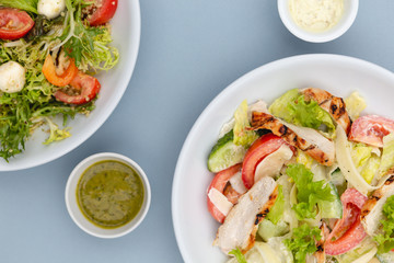 white deep plates with fresh salad ingredients mixed with sauce placed on an attractive background. A place for a menu, banner or advertisement